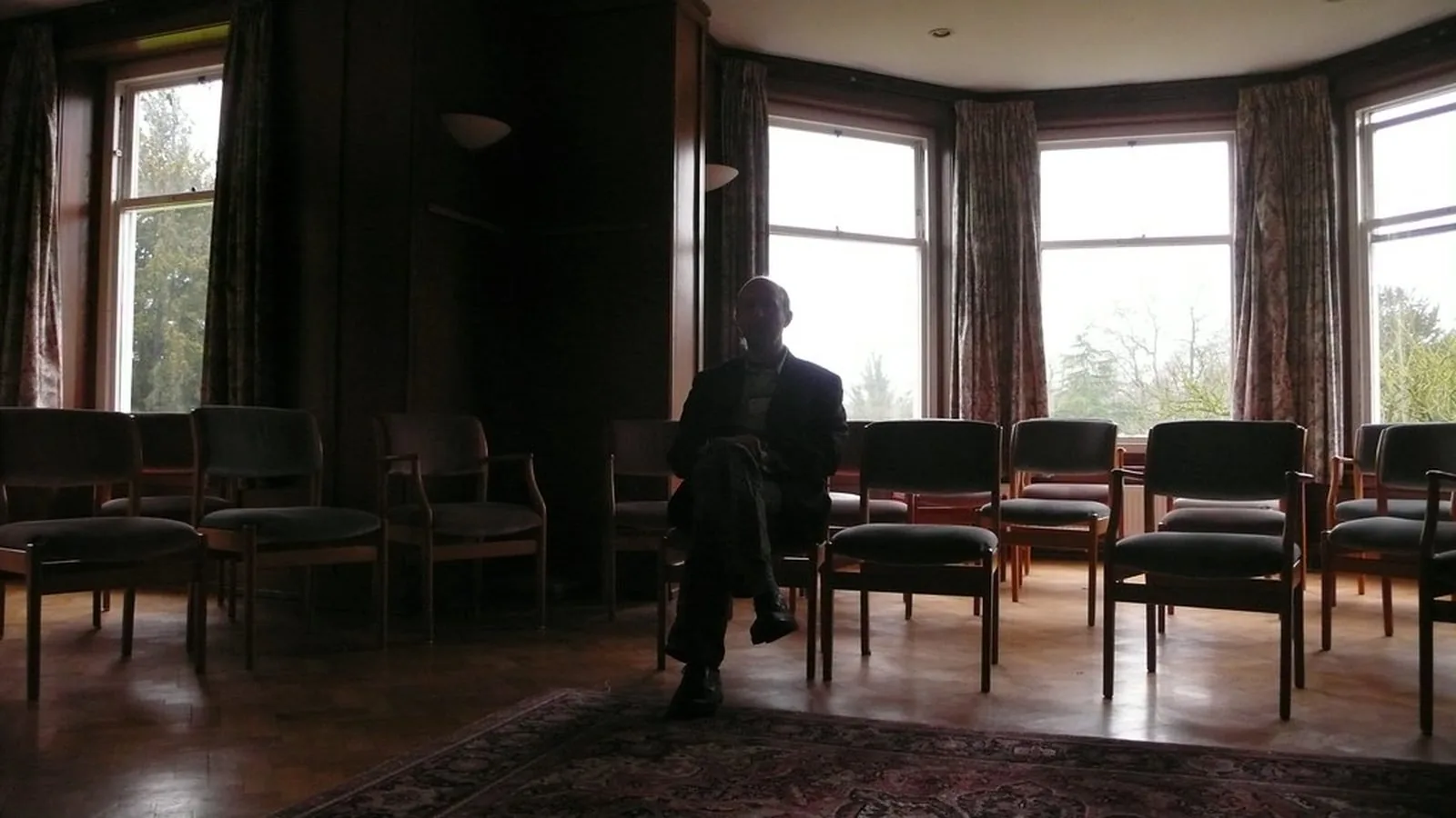 An empty waiting room with chairs arranged along a bay window