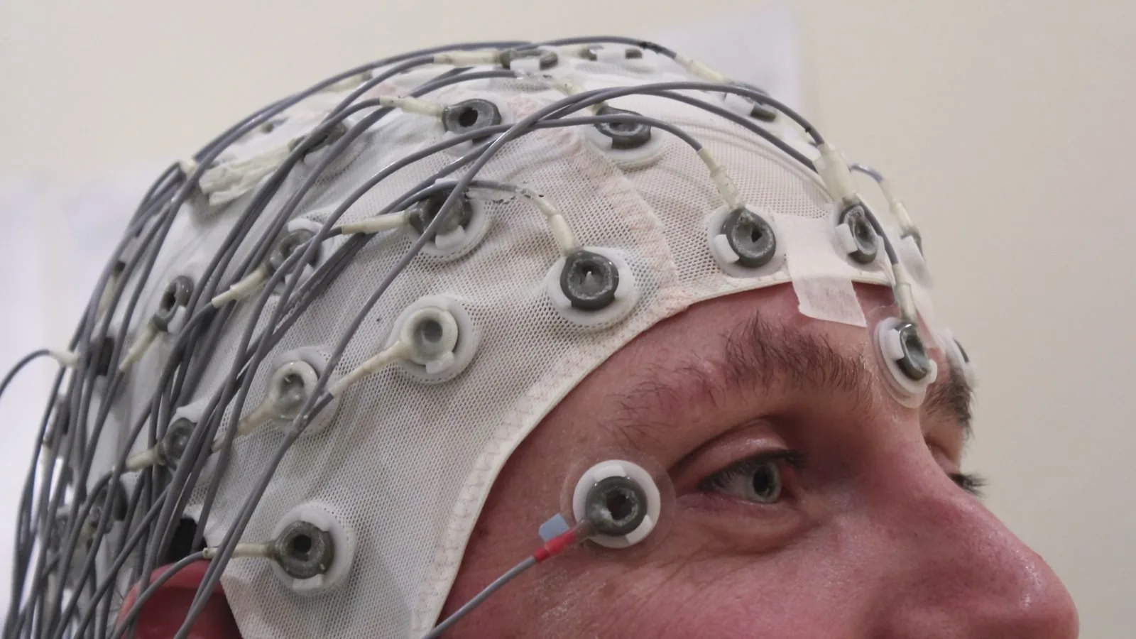 A person wearing an EEG cap covered in electrodes during a research session