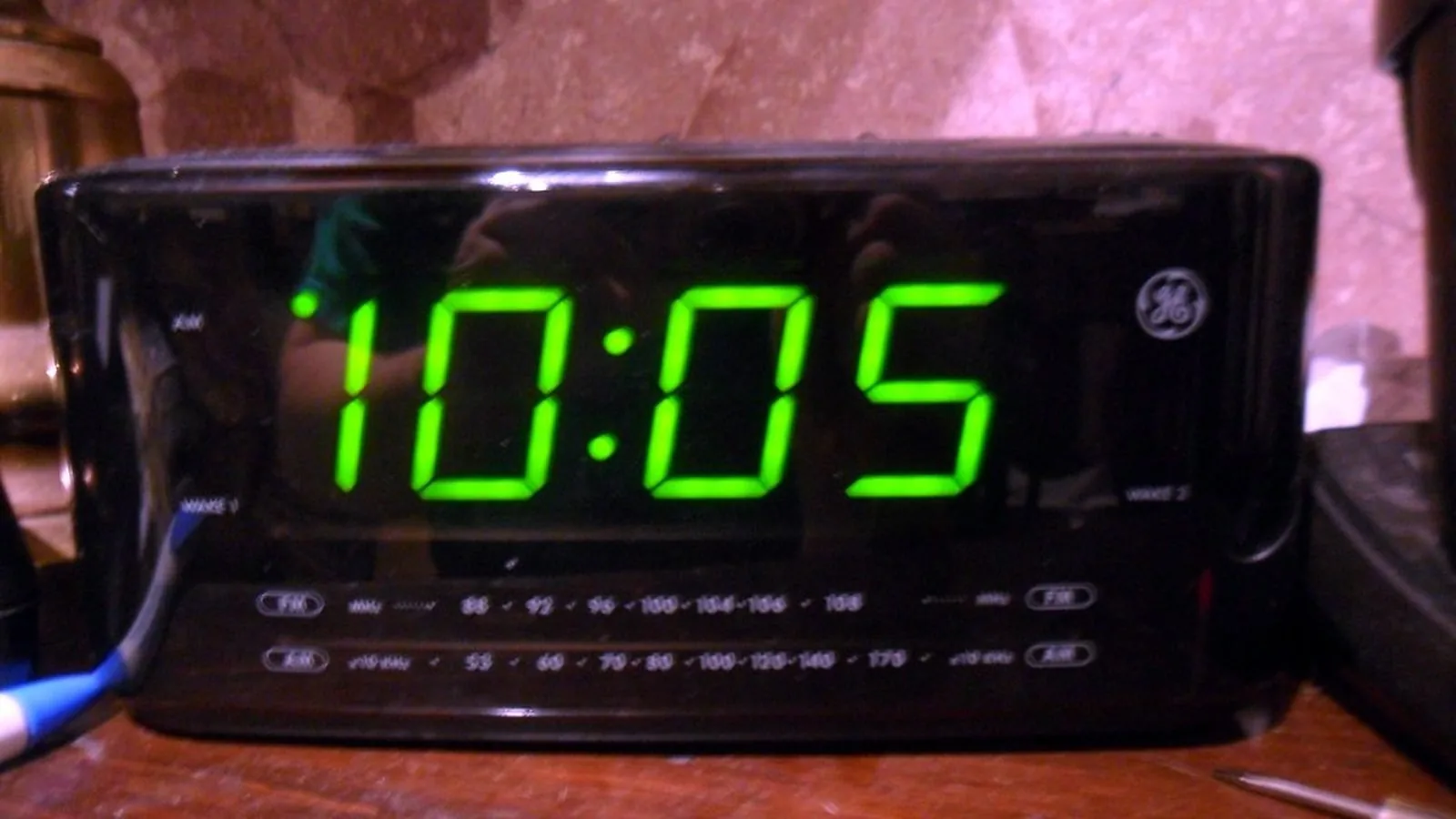 A digital clock radio glowing in a dark room, showing the time after 10pm