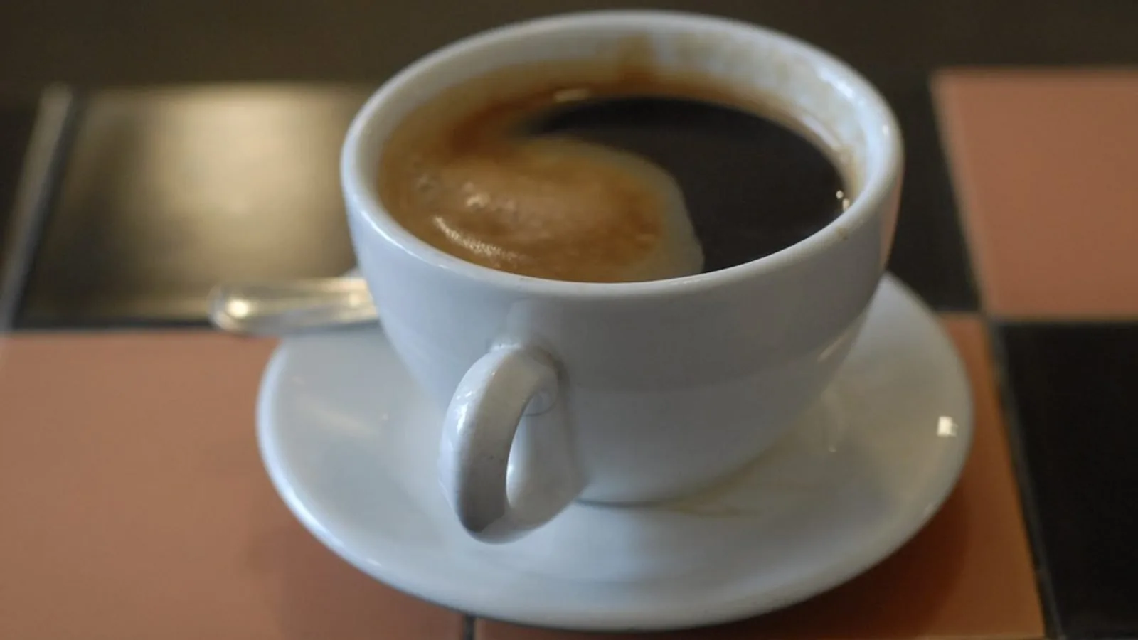 A cup of coffee on a saucer on a table in morning light