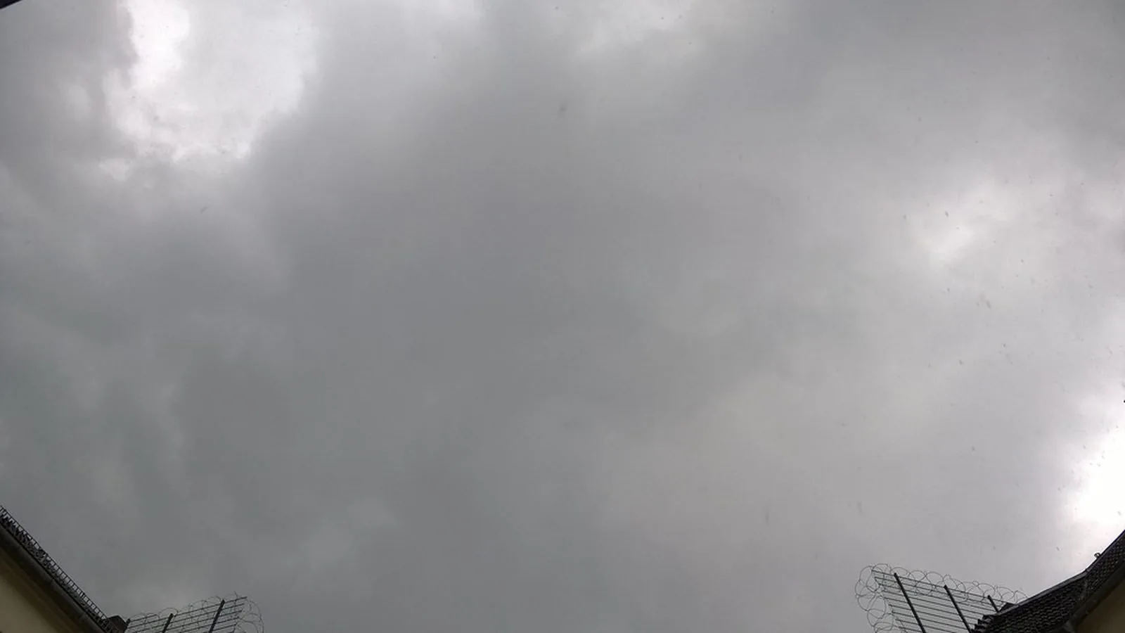 A grey overcast sky seen above the edge of a building