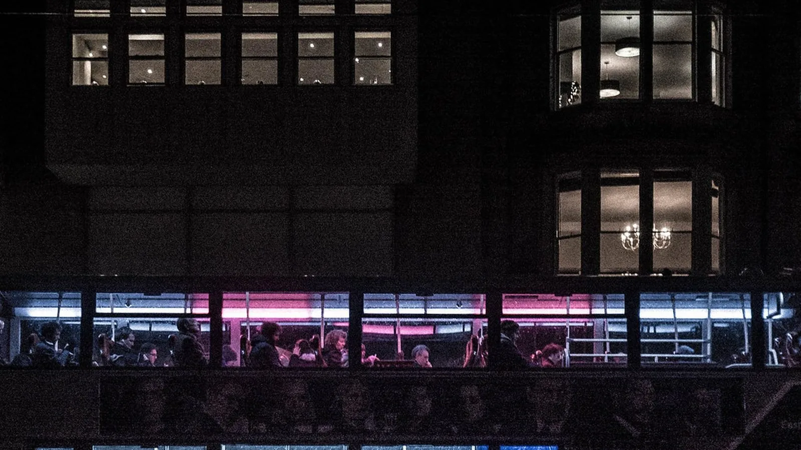 An apartment building at night with several windows still lit